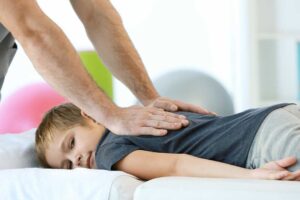 A chiropractor performing a gentle spinal adjustment on a middle-aged patient in a clean, well-lit treatment room.