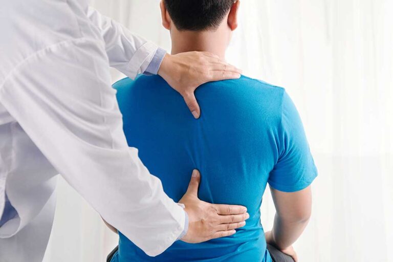 A patient and chiropractor sit together reviewing a chart in a comfortable, sunlit consultation room.